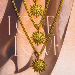 Vintage bohemian triple-layered gold necklaces with abstract sun face pendant on a magazine