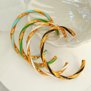 Detail of twisted enamel cuff bracelets in green white and black with gold plating