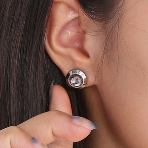 Close-up of a silver stainless steel stud earring with faceted crystal glass on ear