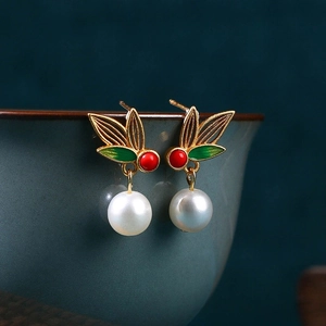 Macro detail of Chinese style pearl earrings with enamel butterfly and gold leaf design