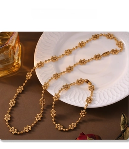 Detail of PVD plated gold necklace and bracelet set featuring floral bead clusters