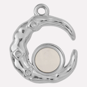 Macro shot of silver crescent moon pendant with white shell inlay and rhinestones