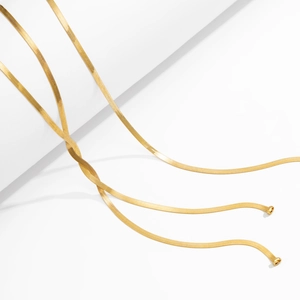 Detailansicht eleganter goldener Schlangenkette auf weißen geometrischen Stufen
