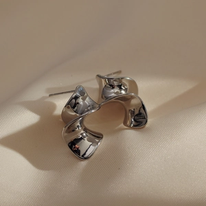 Minimalist silver wavy spiral metal earrings on white silk fabric for a modern stylish look