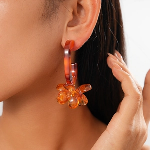 Detail of amber resin flower earring with tortoiseshell C-hoop on model's ear