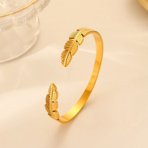 Detailed view of the gold feather-shaped open cuff bracelet in stainless steel