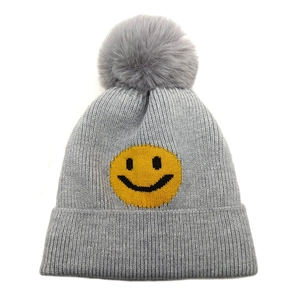Detailansicht der grauen Strickmütze mit gelbem Smiley-Gesicht und flauschigem Pompon