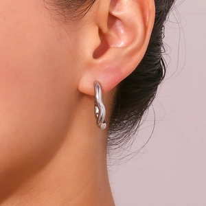 Macro view of wavy silver earrings with minimalist irregular lava texture and metallic luster