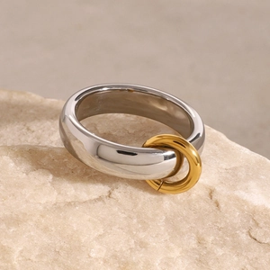 Detail of minimalist two-tone silver and gold stainless steel ring on a natural stone