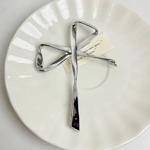 Detailed view of a silver metallic bow brooch on a decorative white porcelain plate