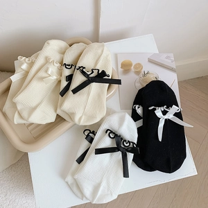 Detail of knit socks featuring wavy ruffle cuffs and contrasting satin bow decorations
