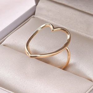 Detailed view of a golden minimalist heart-shaped open ring on a soft jewelry box