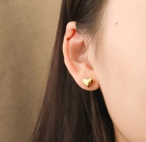 Close-up of heart-shaped gold studs showing polished texture and elegant fit on ear