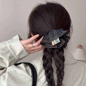 Blue denim scrunchie with yellow stitching shown on a braided hairstyle for women