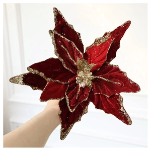 Detail of dark red velvet Christmas flower with gold glitter edges held by hand
