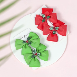 Detail of Christmas bow hair clips with holly leaf decor on a display card
