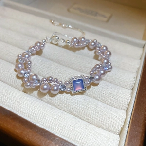 Détail d'un bracelet de perles lavande avec pierre carrée dans un écrin à bijoux élégant