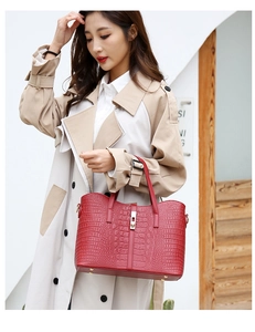 Detail of red crocodile pattern handbag with metal buckle held by model in trench coat