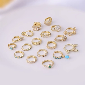 Assorted gold ear cuffs with cubic zirconia and pearls on a white display plate