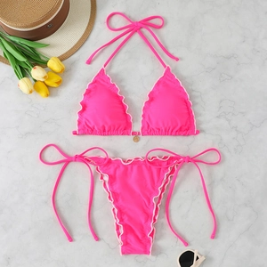 Close-up of rose red halter bikini with ruffled edges and gold ring detail on marble