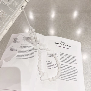 Detail of white heart-shaped beads and ribbon on a transparent phone case strap
