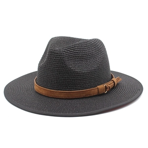 Détail d'un chapeau de paille noir avec ruban marron, boucle dorée et pompon décoratif