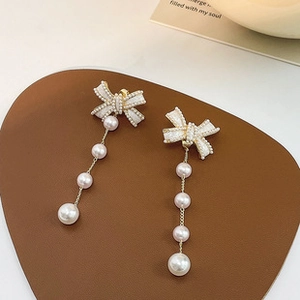 Macro detail of S925 silver bow earrings with elegant long white pearl tassels