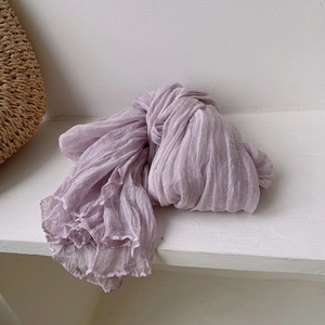 Detail showing soft pleated texture of light purple scarf on white wooden shelf
