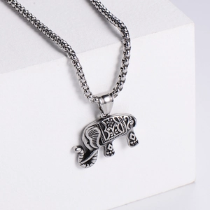 Macro detail of vintage elephant pendant with intricate geometric patterns on box chain
