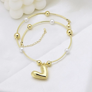 Elegant gold chain bracelet with white pearls and polished heart pendant on white silk