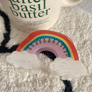 Close-up of rainbow and cloud acrylic hair claw clip on soft white plush background