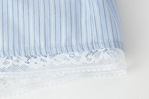 Detail of light blue striped fabric with delicate white lace trim and cotton texture
