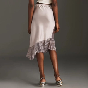 Detail of light pink satin skirt featuring asymmetric lace trim and elegant hemline