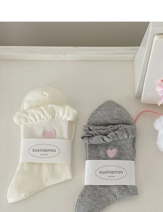Close-up of white and grey ruffled socks featuring cute pink heart embroidery details
