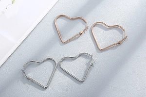 Macro detail of heart shaped hoop earrings with twisted rope texture in gold and silver