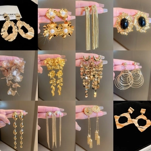 Detailed close-up of golden floral earrings with long fringe tassels and coin motifs