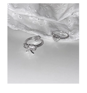 Close-up of S925 sterling silver bowknot and scalloped heart rings on lace fabric