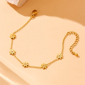 Golden stainless steel daisy flower bracelet displayed on a minimalist beige background