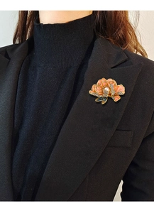Detail of pink enamel peony brooch with pearl accent on a black blazer lapel
