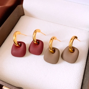Detail view of matte burgundy and khaki trapezoid earrings on white velvet