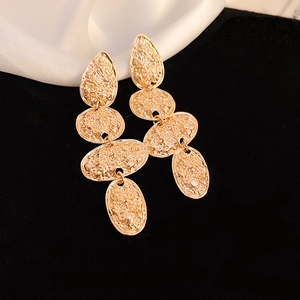 Macro shot of gold-plated drop earrings featuring vintage hammered metal texture details