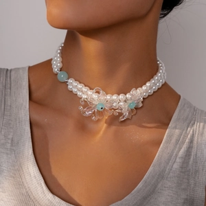 Macro shot of double-layer pearl necklace with iridescent acrylic flowers and blue bead