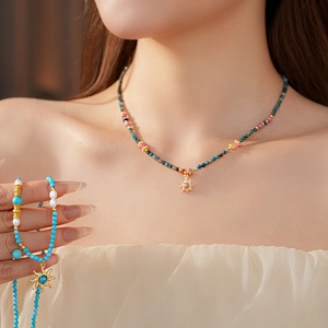 Détail du collier de perles en turquoise avec pendentif soleil porté sur un mannequin