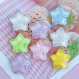 Flat lay of colorful glitter resin star charms in pink, blue, and yellow for DIY crafts