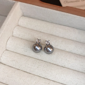 Détail de boucles d'oreilles perles grises avec zircon dans un écrin en velours