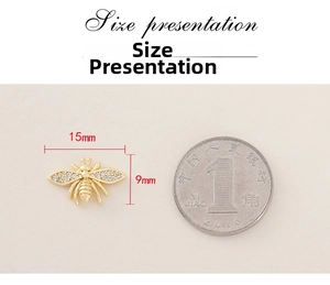 Detailed size view of a gold bee pendant with zircons next to a coin for scale