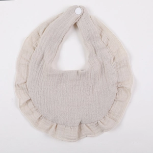 Detail of beige ruffle baby bib with breathable cotton texture and secure snap button