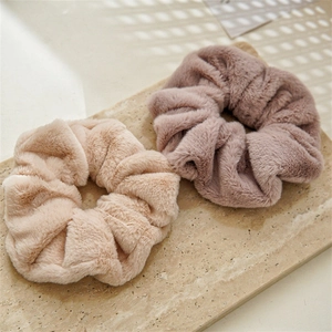 Set of beige and dusty pink rabbit fur hair scrunchies on a stone slab background