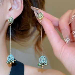 Close-up of floral tassel earrings with blue enamel petals and dangling chain on model