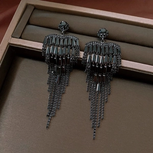 Detailed close-up of luxury black rhinestone bow tassel earrings in a jewelry box